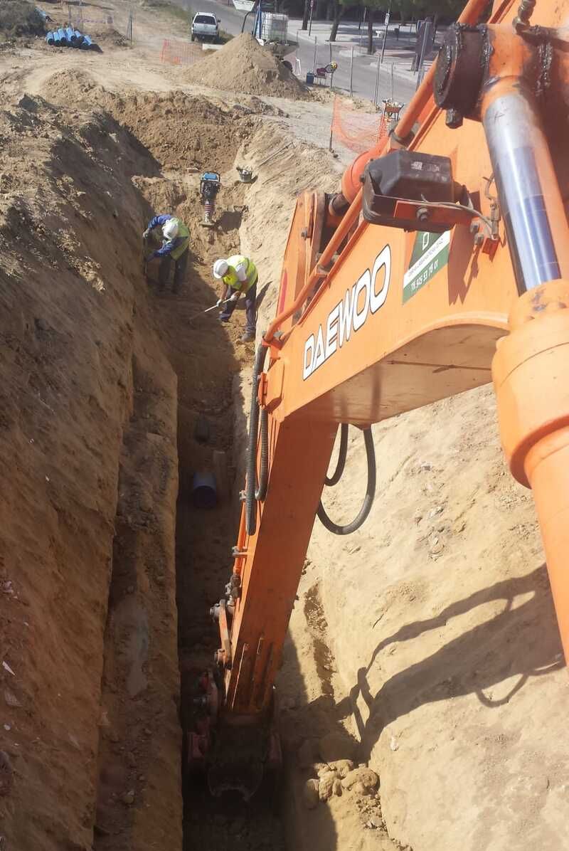 Maquina excavando y dos personas trabajando